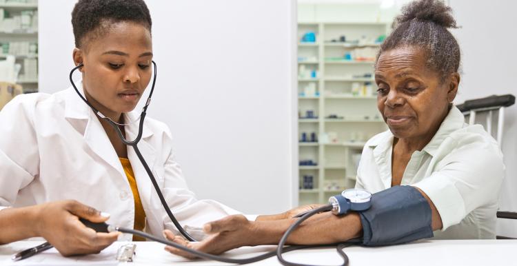 Female pharmacist measuring blood pressure of woman in the pharmacy.