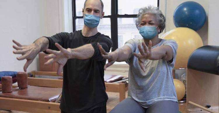 A man and a women sitting on exercise balls. Their arms are stretched out in front of them.