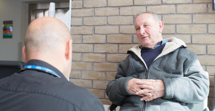 Older man in a hospital setting talking with a doctor