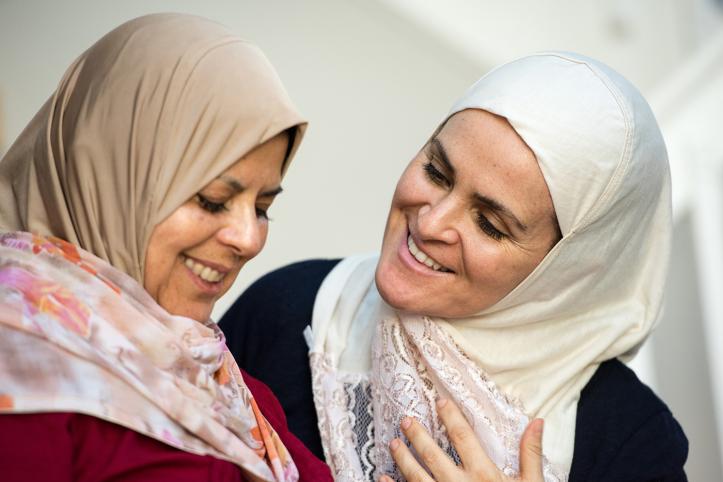 Two muslim women posing smiling talking looking at each other