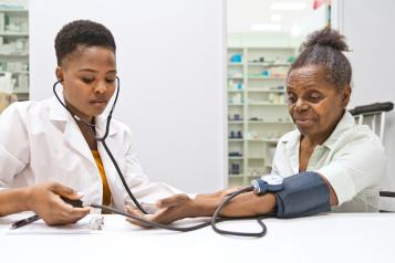 Female pharmacist measuring blood pressure of woman in the pharmacy.