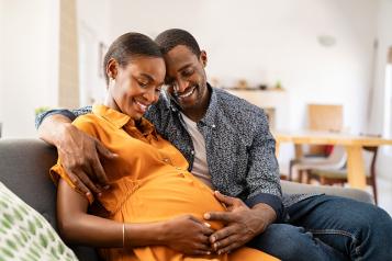 Pregnant woman and her partner sitting on a sofa