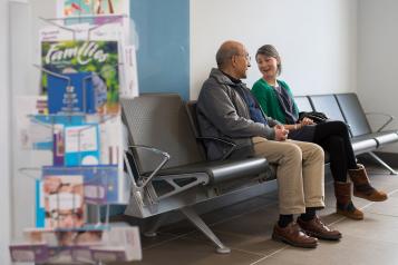 Older man talking to younger woman in a hospital waiting area